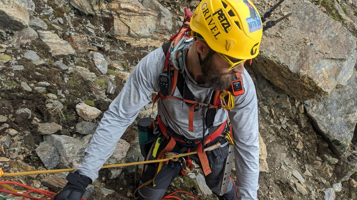 Climber wearing ergonomic head climbing guard while on wellness-focused mountain trek