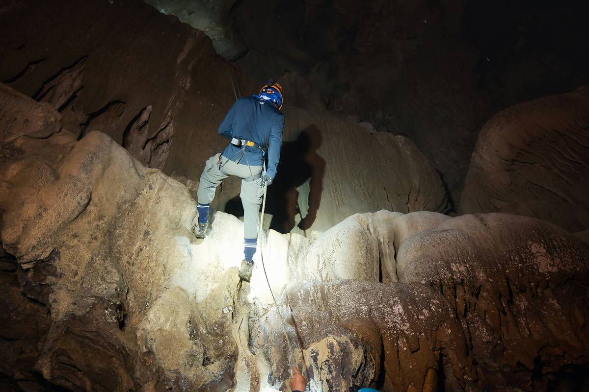 Climber wearing peak helmet shield while ascending icy ridge